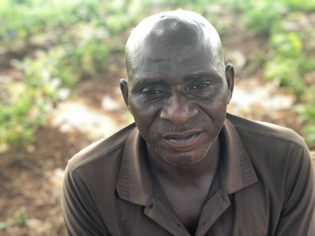 Headshot of an elderly African man wearing a grey-balck T-shirt.